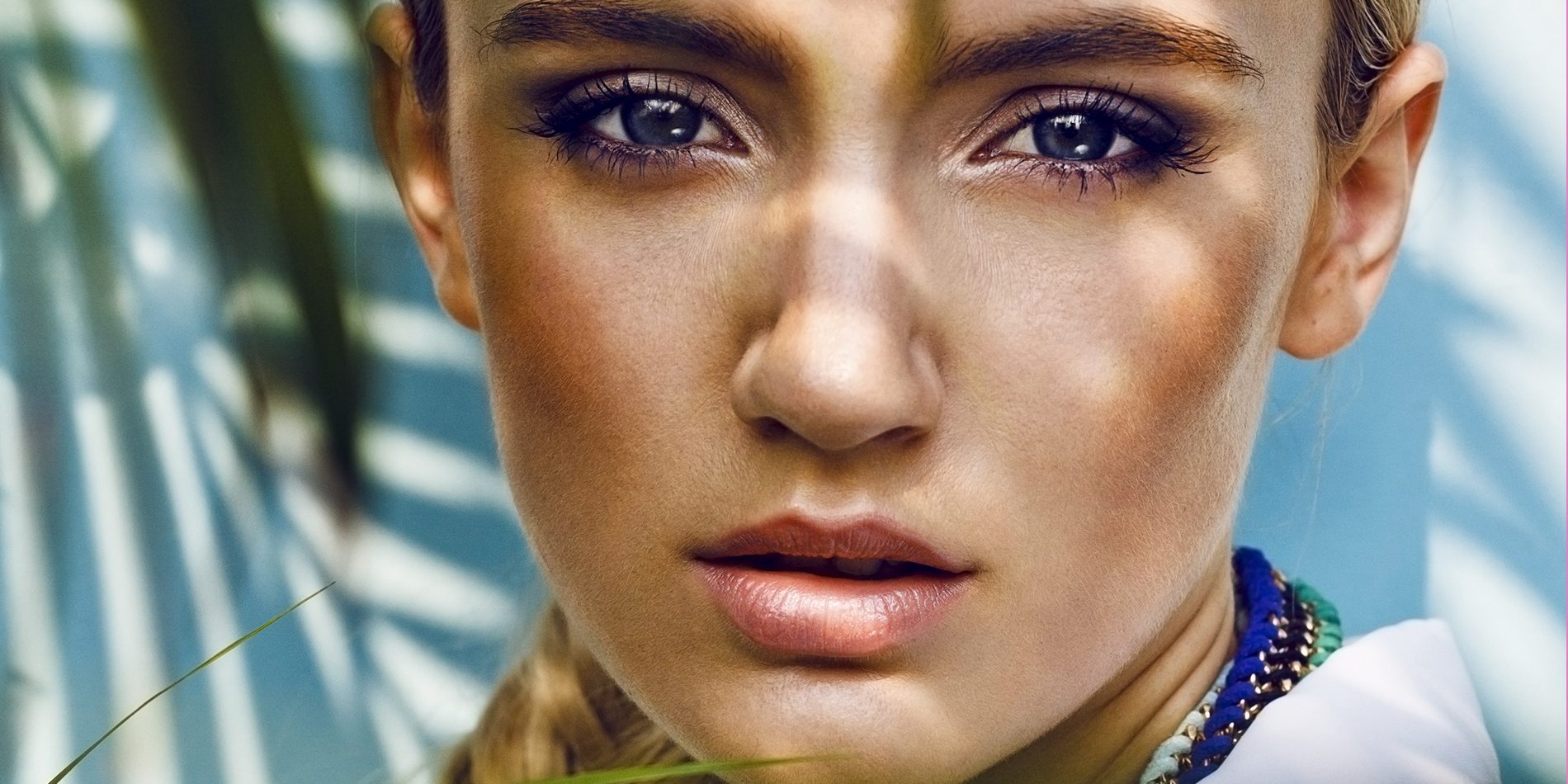 Close up of beautiful fashion model in the jungle scene, thinking while her eager eyes searches for the ray of sun, shadows falling on her face creating a warm lively atmosphere.