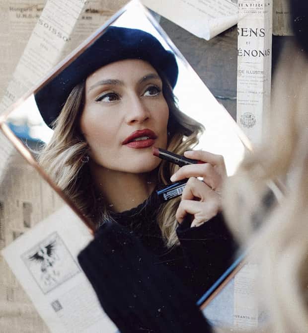 Lima Ché kijkt in spiegel en doet lippenstift op