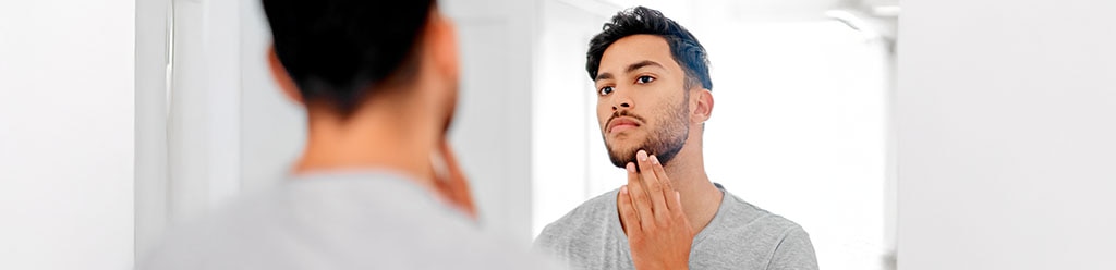 Man met baard kijkt in spiegel
