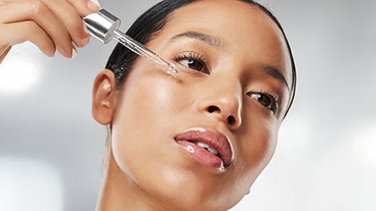 jeune femme brune avec pipette de serum sur visage jeune femme brune avec pipette de serum sur visage