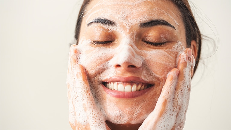 Woman washing her face with cleansing foam Woman washing her face with cleansing foam