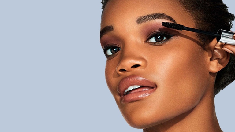 Visage d’une femme en gros plan, une brosse à mascara à la main Visage d’une femme en gros plan, une brosse à mascara à la main